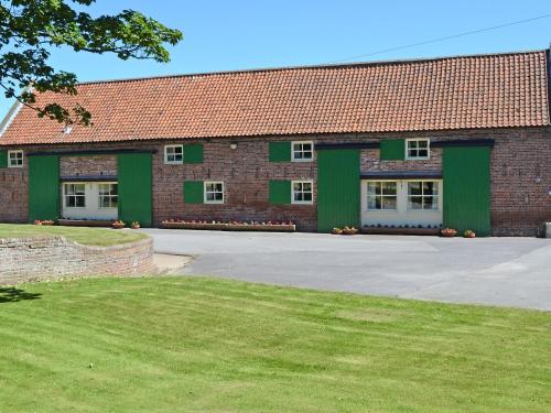 a large red brick building with green doors at Percheron Cottage in Sewerby