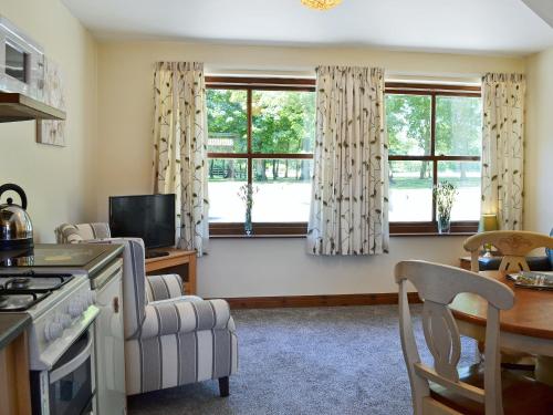 a living room with two windows and a table at Percheron Cottage in Sewerby