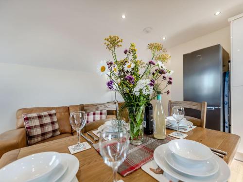 a dining room table with plates and flowers in a vase at Penceunant in Penuwch