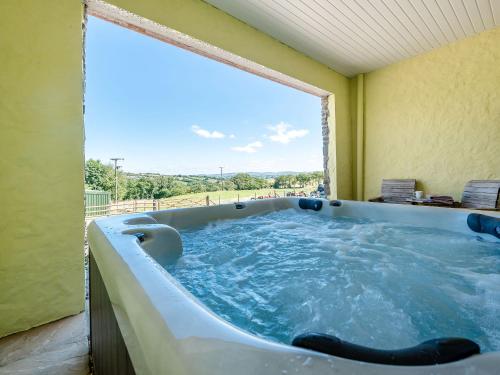 a jacuzzi tub in a room with a large window at Penceunant in Penuwch