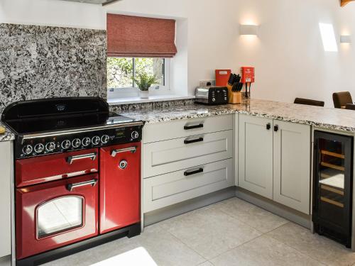 a kitchen with a red stove and white cabinets at Lower Stables in Newlyn