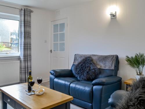 a blue leather chair in a living room with a table at Anchor Cottage in Portpatrick