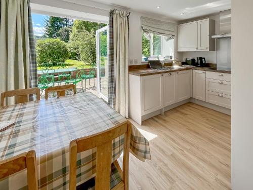 a kitchen with a table and a large window at Hillview Cottage in Aberfeldy
