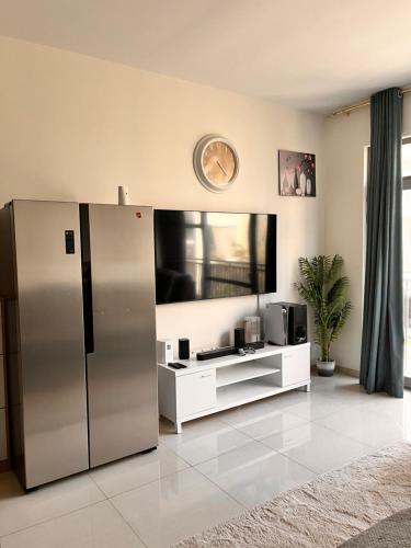 a kitchen with a refrigerator and a tv on the wall at The Opal residence IBR in Sharjah