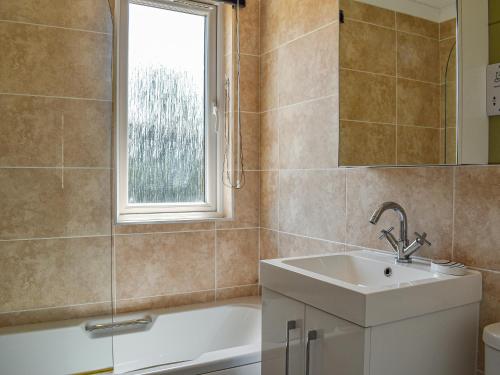 a bathroom with a sink and a tub and a window at Buckland Lodge in Pentridge