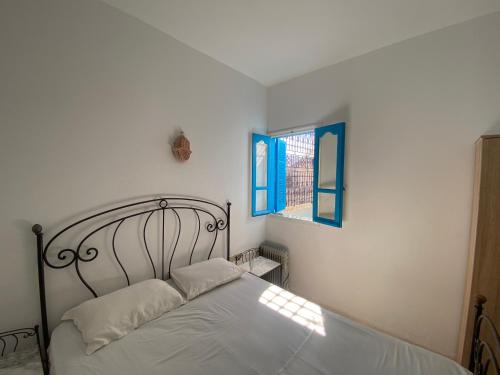 a bedroom with a bed with white sheets and a window at Dar El Jasmin - Étage de Villa à Djerba Houmt Souk in Houmt Souk