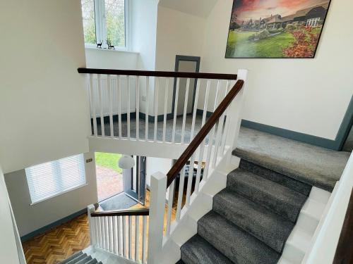 a staircase in a home with white walls and wood floors at Warren Lodge in Little Baddow