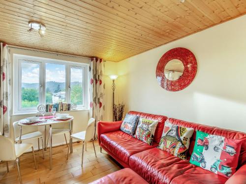 Una sala de estar con un sofá rojo y una mesa. en Strawberries And Cream, en Bowness-on-Windermere