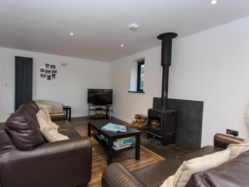 a living room with a couch and a wood stove at Willow Barn - Fernhill Farm in Wootton Bridge