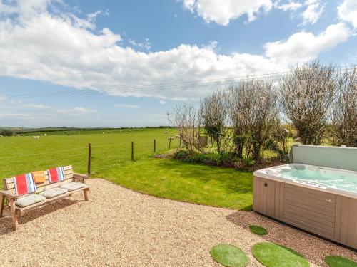Un jacuzzi y un banco al lado de un campo. en Hafan Fach - Cottage, en Pembroke