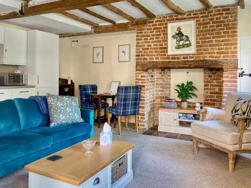 a living room with a blue couch and a brick wall at The Yeomans Cottage, Eastbridge Hospital in Canterbury
