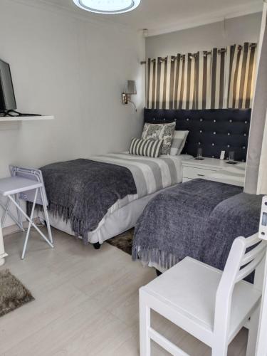 a bedroom with two beds and a chair at Marula Guest House Unit 1 in Durban