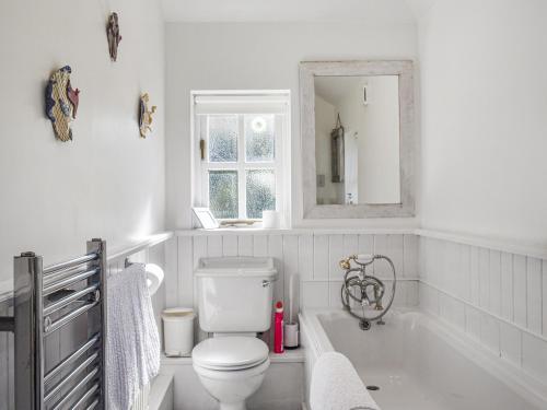 a bathroom with a toilet and a tub and a mirror at No Place in Sennen
