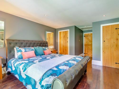 a bedroom with a large bed with blue and pink pillows at Forest View Barn in Balcombe