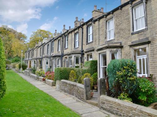 a row of brick houses with bushes and grass at Ivy Cottage in Skipton