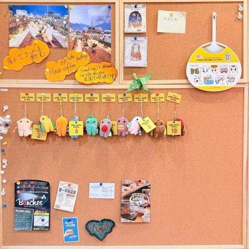 a bulletin board with toys and pictures on a wall at KOBE coffee hostel in Kobe