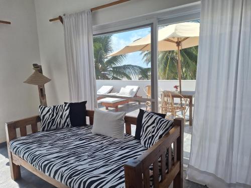 a bedroom with a bed and a balcony with an umbrella at Nakupenda Malaika Flat in Pwani Mchangani