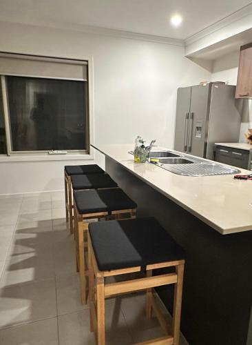 a kitchen with a counter with chairs and a sink at Stylish four bedroom family retreat in Saltwater Coast in Point Cook