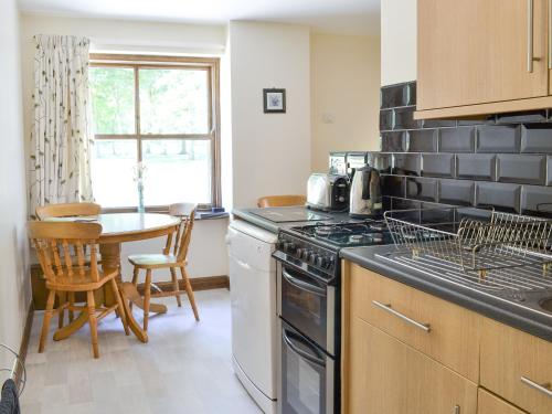 a kitchen with a stove and a table in it at Clydesdale Cottage in Sewerby