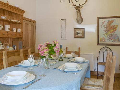 a dining room with a table with plates and glasses at Hill View House in Aberfeldy