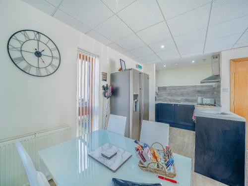 a kitchen with a table and a clock on the wall at 1 Ladyknowe - Uk39970 in Moffat
