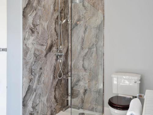 a shower with a glass door next to a toilet at Craigvar House in Castle Douglas
