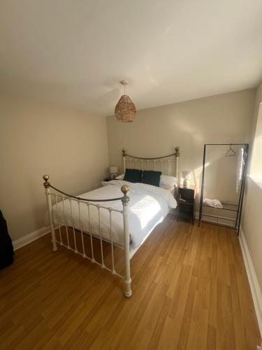 a bedroom with a white bed and a wooden floor at Open plan flat with large garden close to beach in Bournemouth