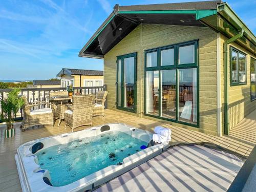 a hot tub on a deck next to a house at Victoria Lodge - Uk35820 in Llanddulas