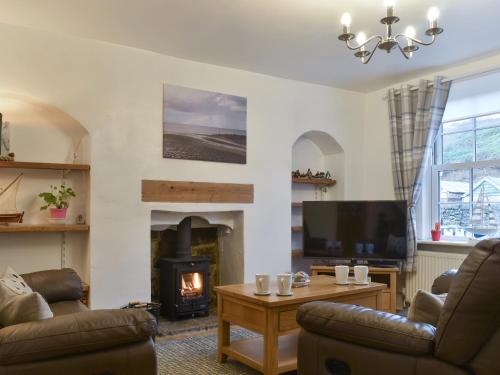 ein Wohnzimmer mit Kamin und Fernseher in der Unterkunft Quaker's Cottage in Carlin How