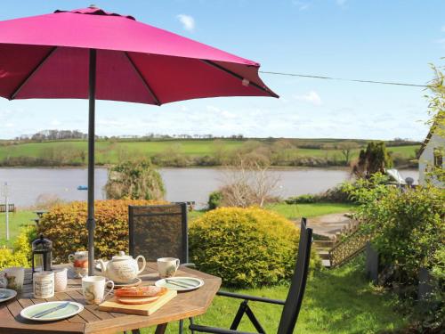 a picnic table with an umbrella and a river at Teifi View in Cardigan
