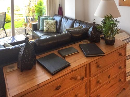 ein Wohnzimmer mit einer Ledercouch und einer Holzkommode in der Unterkunft Teifi View in Cardigan