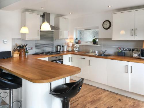 a kitchen with white cabinets and a wooden counter top at Teifi View in Cardigan