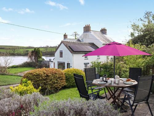 einen Tisch mit einem Sonnenschirm im Garten eines Hauses in der Unterkunft Teifi View in Cardigan