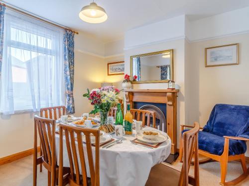 a dining room with a table and chairs and a fireplace at Mayflower Cottage in Harwich