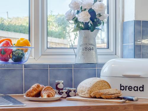 a kitchen counter with bread and a vase of flowers at Mayflower Cottage in Harwich