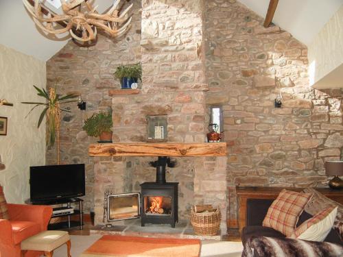 ein Wohnzimmer mit einer Steinmauer und einem Kamin in der Unterkunft Garden Cottage in Pooley Bridge