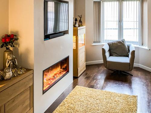 a living room with a fireplace and a chair at Chestnut House in Bridgend