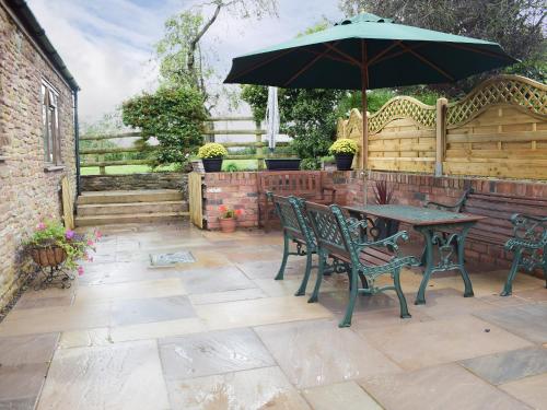 a table and chairs with an umbrella on a patio at The Byre in Pencombe