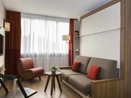 a living room with a couch and a chair at Aparthotel Adagio Genève Mont-Blanc in Geneva