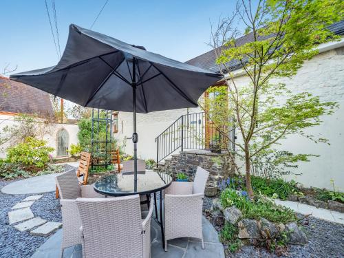 a patio with a table and chairs with an umbrella at The Bothy in Whitland