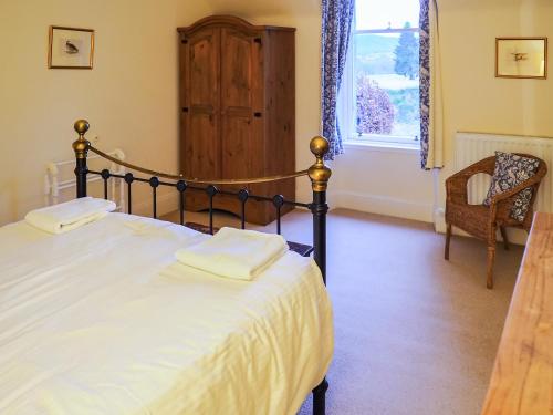 a bedroom with a bed and a chair and a window at Einich in Newtonmore