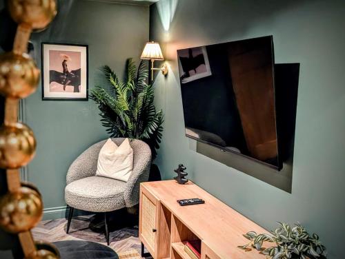sala de estar con silla y TV de pantalla plana en The Hideaway Bureau - Campbeltown, en Wooler