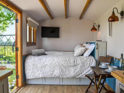 a bedroom with a bed with a television on the wall at Wildflower View in Lowthorpe