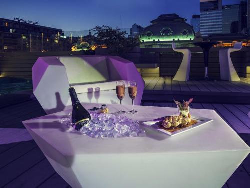 a table with wine glasses and a plate of food at Mercure Santiago Centro in Santiago