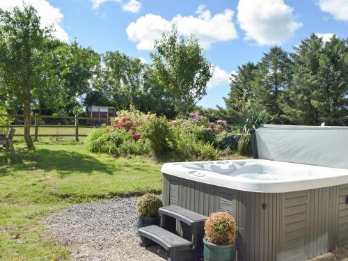 una bañera de hidromasaje en un jardín con plantas en Hafan Fach Cottage, en Pembroke