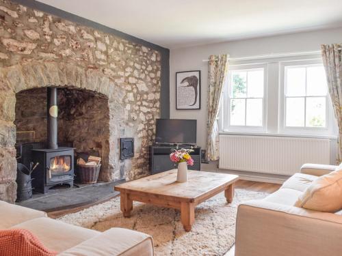 sala de estar con chimenea de piedra y mesa en Hafan Fach Cottage, en Pembroke