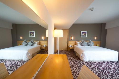 a hotel room with two beds and a couch at The Everly Putrajaya in Putrajaya