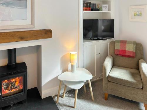 a living room with a fireplace and a chair and a stove at Southbank Cottage in Errol