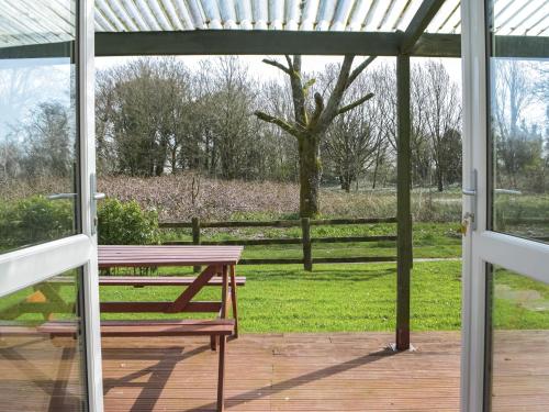 a porch with a picnic table and a tree at Beachside in Llanstephan