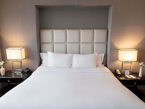 a bedroom with a large white bed with two lamps at Pullman Sao Paulo Vila Olimpia in Sao Paulo
